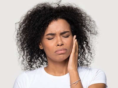 A woman holds her jaw in pain.