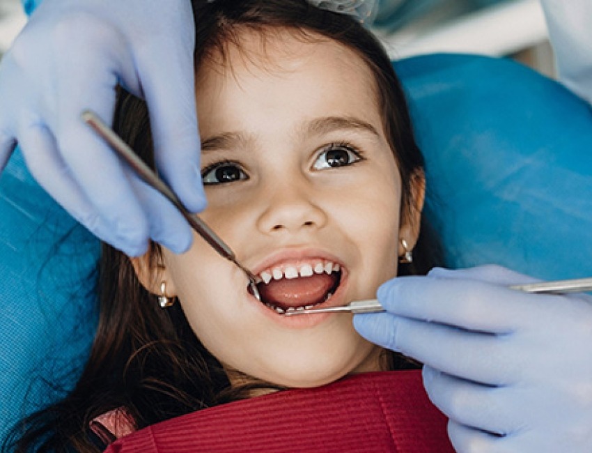 A little girl gets her teeth examined at the dentist.