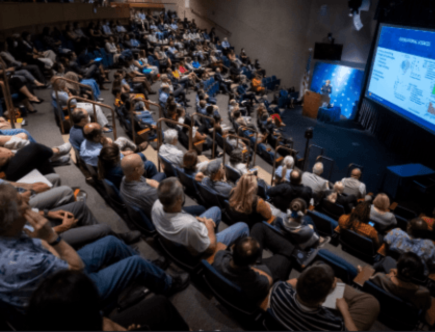 Many individuals gathered in a lecture hall, engaged in a presentation or discussion.