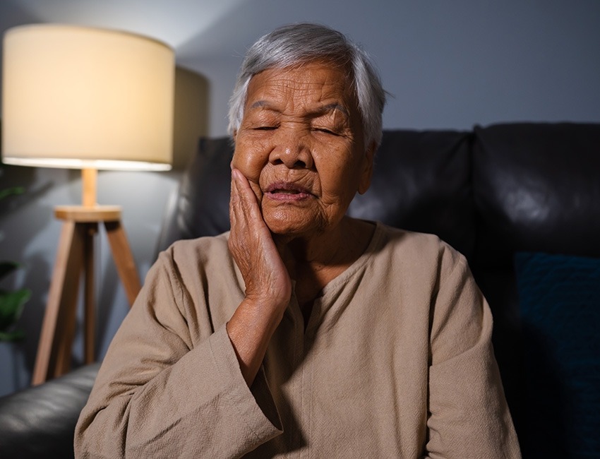 An older woman experiencing mouth pain.