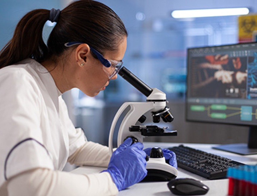 A scientist looking through a microscope.