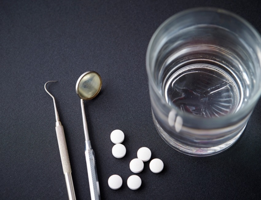 A glass of water, some pills, and dental instruments.