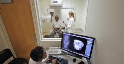Patient receiving CT scan while researcher reviews the scan in another room
