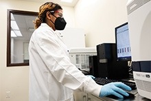 A female scientist wearing a white lab coat in a laboratory setting.