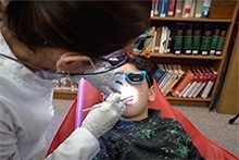 A dentist in a white lab coat with a child patient during a dental check-up.