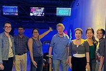 A diverse group of individuals posing in front of a bowling alley, ready for a fun-filled game.