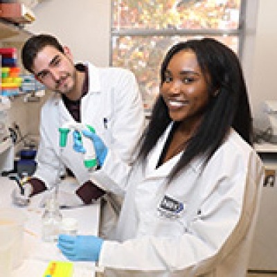 Two scientists wearing lab coats standing together in a laboratory.